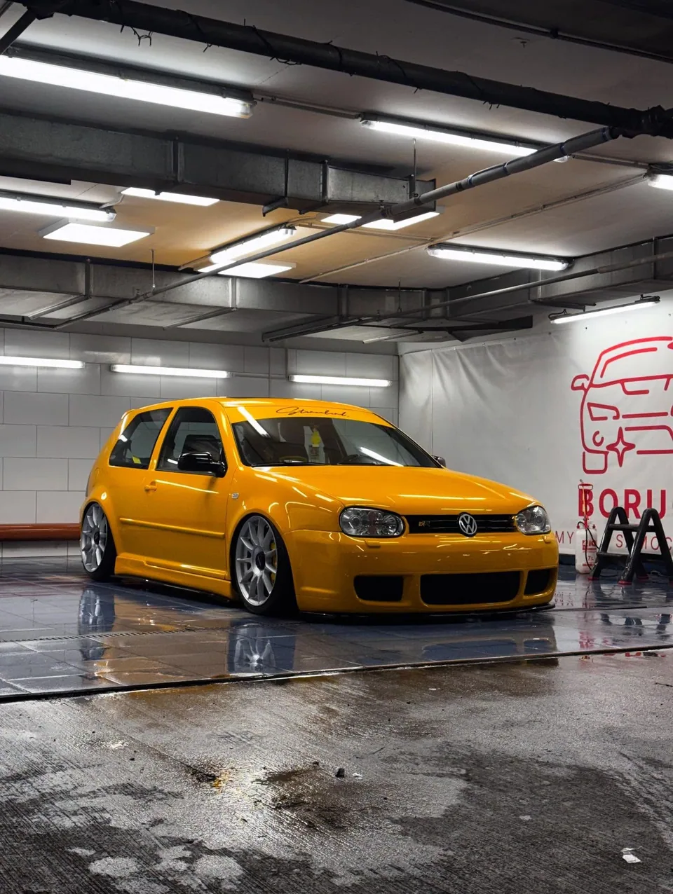 Żółty Volkswagen Golf na mokrej posadzce Boruch Myjnia